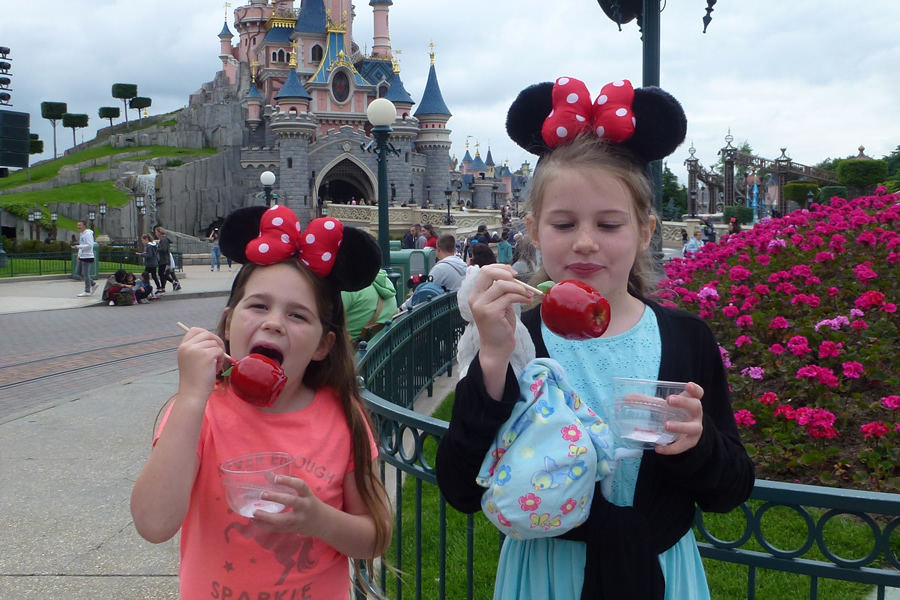 Kids eating toffee apples in front of Disneyland Paris Castle