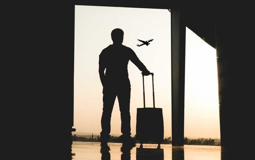 Silouet of man in airport terminal watching aircraft take-off
