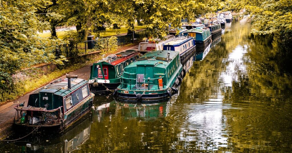 Canal boats alongside the towpath in a London park setting